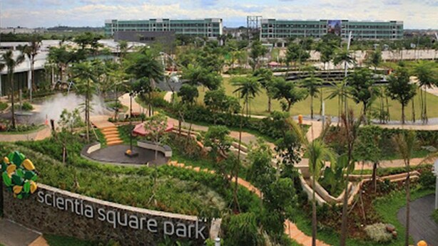 Un panneau indiquant le parc de Scientia Square, avec un espace paysager, des palmiers et un bâtiment en arrière-plan.