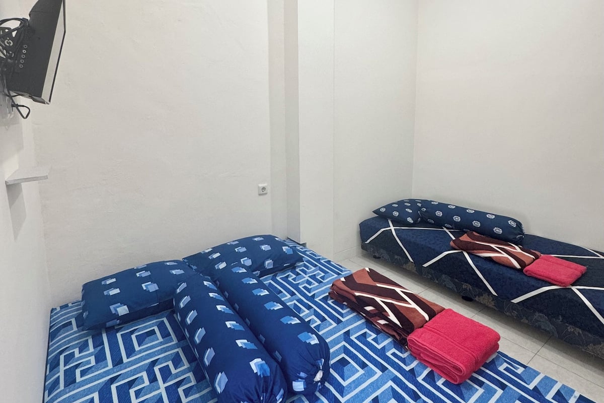 Una habitación con una cama, un sofá y un televisor montado en la pared.