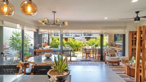A modern dining area with a glass table, chairs, and a potted plant. - Vista Natura 54 | Beach Access | Rooftop Deck | Gated Community | Pool & Hot Tub (Nuevo Vallarta)