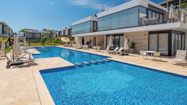 A modern pool area with lounge chairs and umbrellas, surrounded by contemporary buildings. - Vista Natura 54 | Beach Access | Rooftop Deck | Gated Community | Pool & Hot Tub (Nuevo Vallarta)