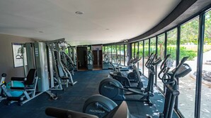 Une salle de sport équipée de machines de cardio, de postes d’entraînement avec poids et de miroirs.