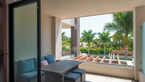 Un balcon avec un canapé et une table, une vue sur les palmiers et une piscine, et un design architectural moderne.