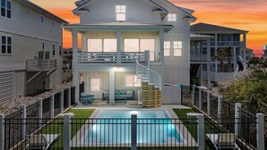 A two-story house with a balcony, a swimming pool, and a well-maintained lawn. - The Pointe of No Return (Ocean Isle Beach)