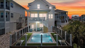 A two-story house with a balcony, a swimming pool, and a view of the sunset. - The Pointe of No Return (Ocean Isle Beach)