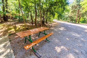 A picnic table with benches in a shaded area surrounded by trees.
