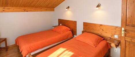 A room with two wooden beds, a wooden ceiling, and a wooden wardrobe.