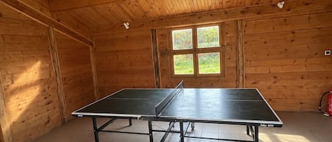 A ping pong table in a room with wooden walls and a tiled floor.