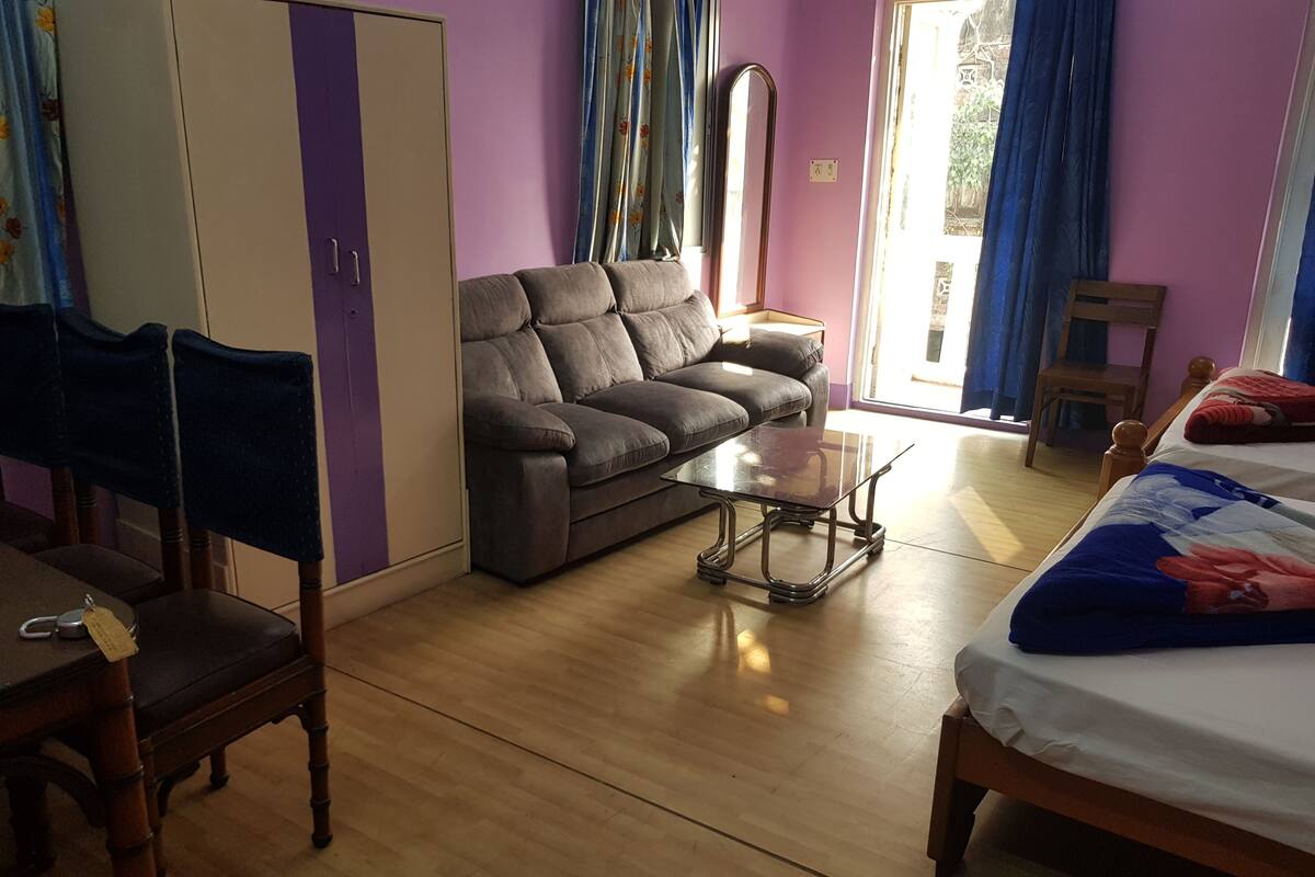 A room with a sofa, a small table, a bed, a chair, and a wardrobe.
