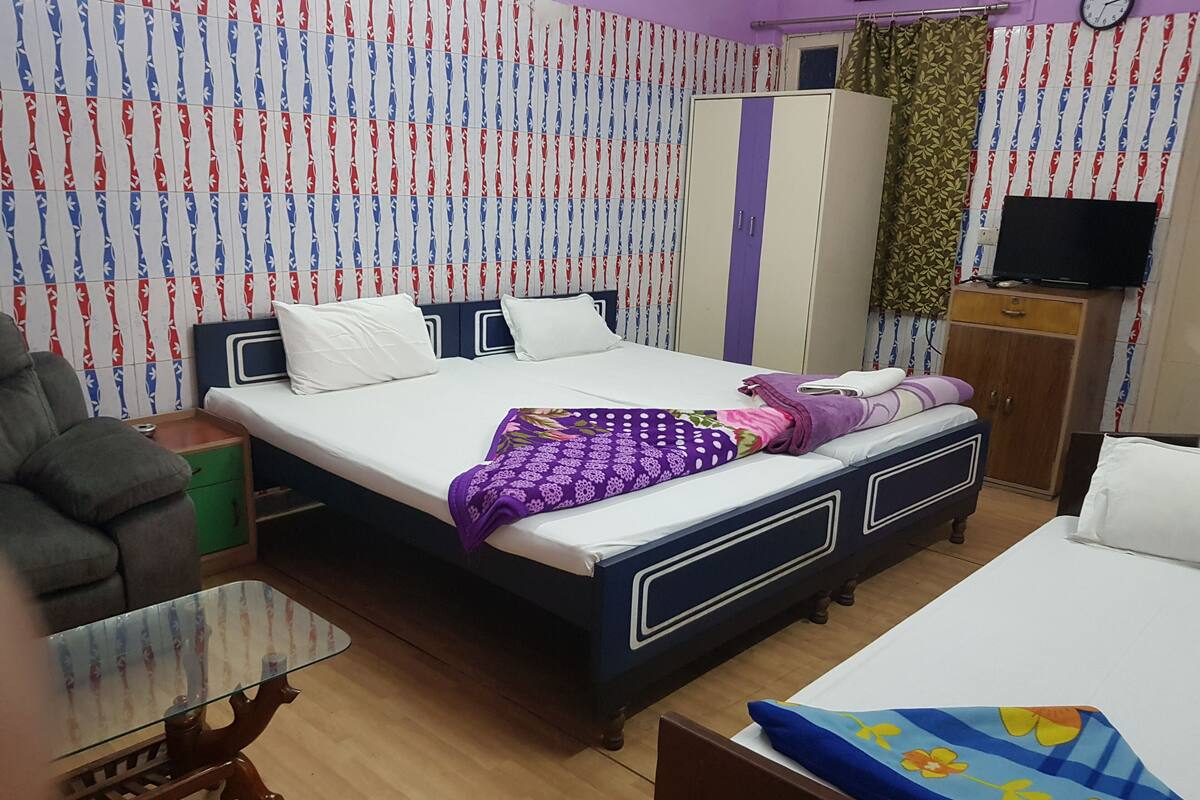 A bedroom with a bed, a wardrobe, a TV, and a desk.