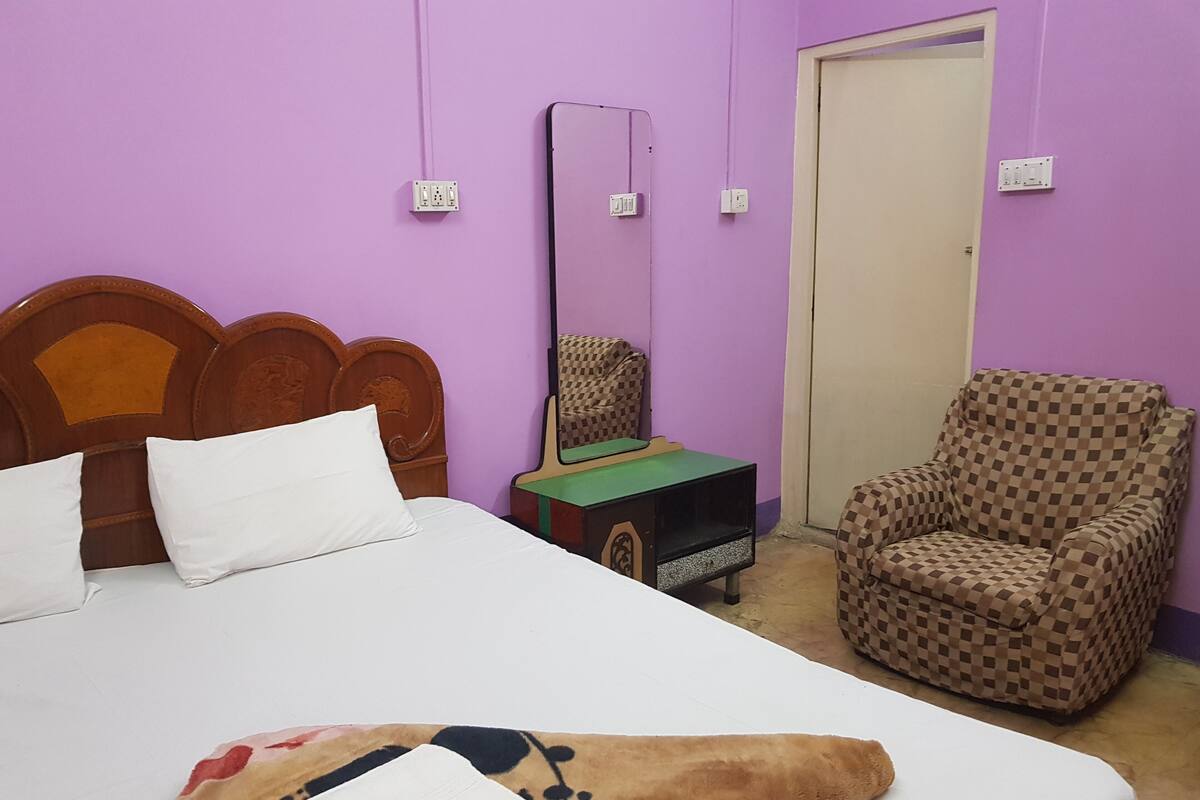 A room with a bed, a chair, and a small table with a green surface.