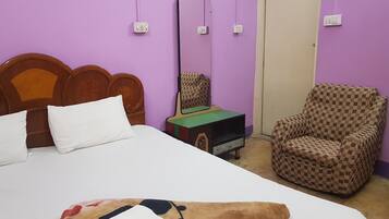 A room with a bed, a chair, and a small table with a green surface.