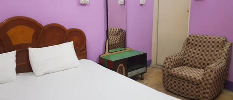 A room with a bed, a chair, and a small table with a green surface.