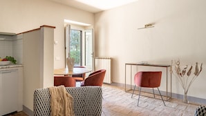 Une cuisine moderne avec un coin repas, comprenant une table ronde, des chaises rouges et une vue à travers une porte vitrée.