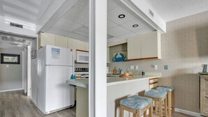 Una cocina con refrigerador, microondas y taburetes de madera.
