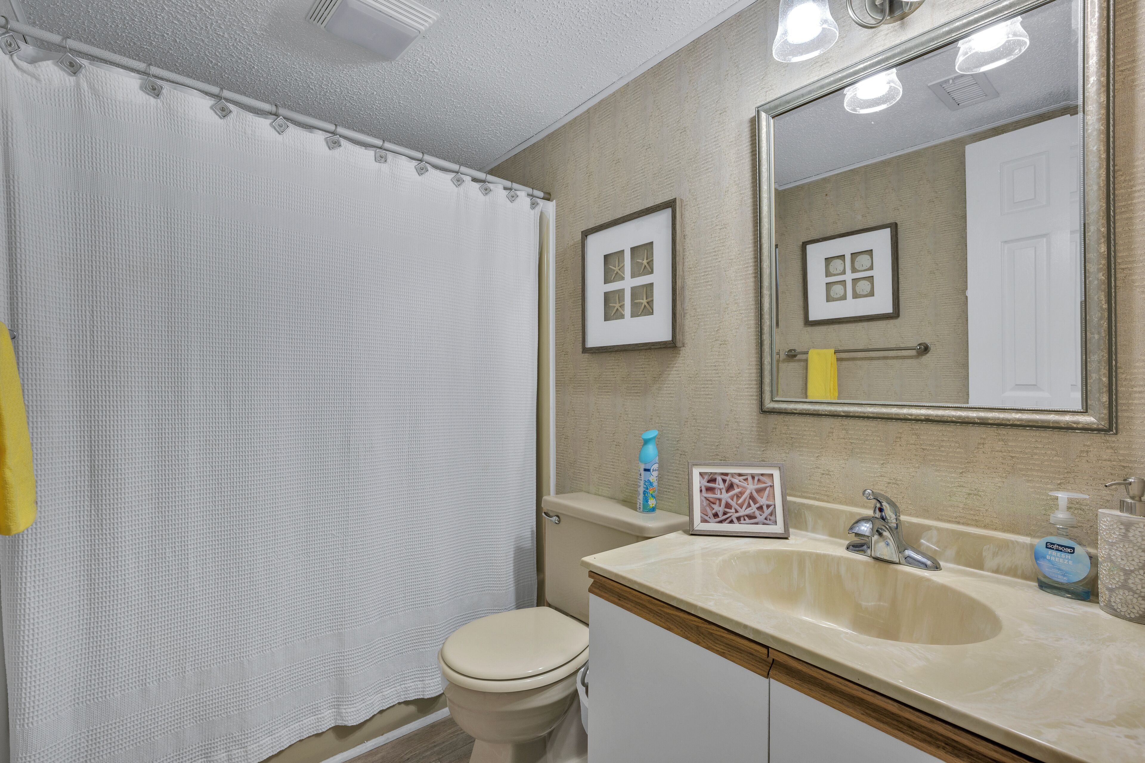 Een badkamer met toilet, wastafel, spiegel en douchegordijn.
