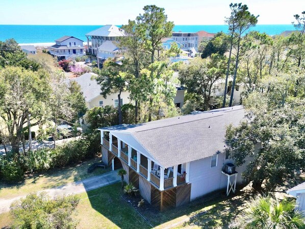 A coastal property with a large house, a deck, and a view of the ocean.