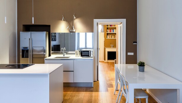 A modern kitchen with stainless steel appliances, a white countertop, and a wooden floor. - Bramante Luxury Apartments by InnStay (Milan)