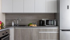 Una cocina moderna con armarios grises, un refrigerador de acero inoxidable, un microondas y un fregadero.