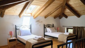 Una habitación con dos camas, pisos de madera, tragaluces y una ventana.