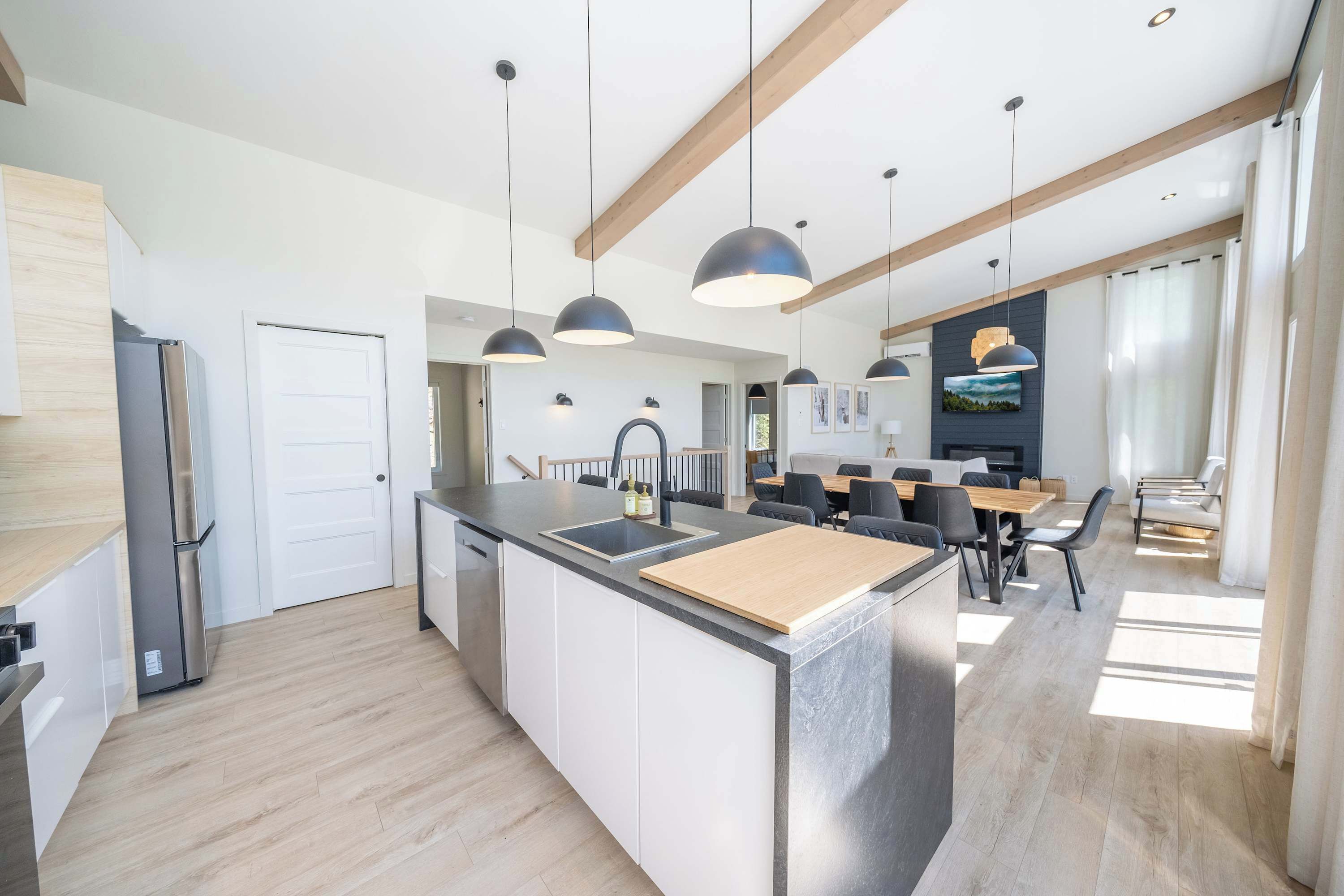 Uma cozinha moderna com ilha central, eletrodomésticos embutidos e iluminação pendente.
