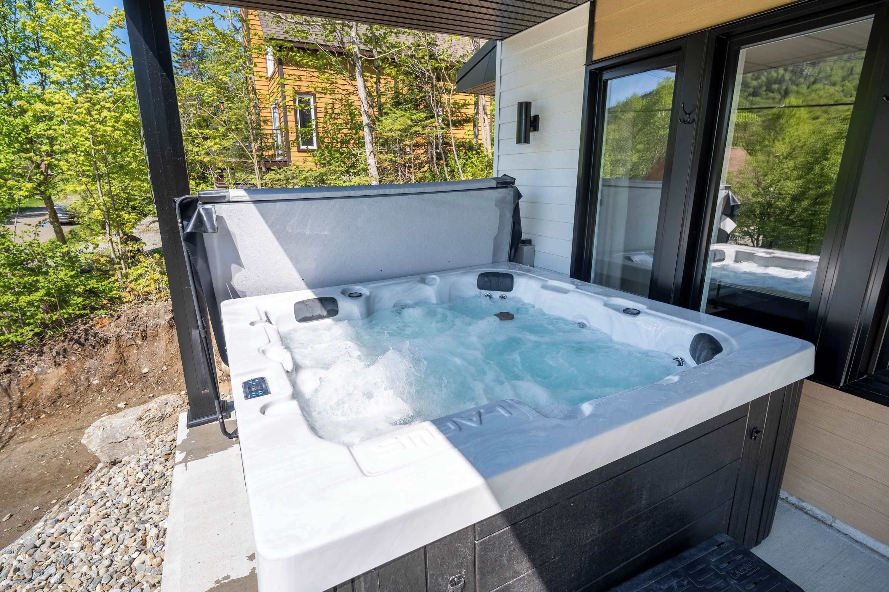 A hot tub with a view of a building and trees.