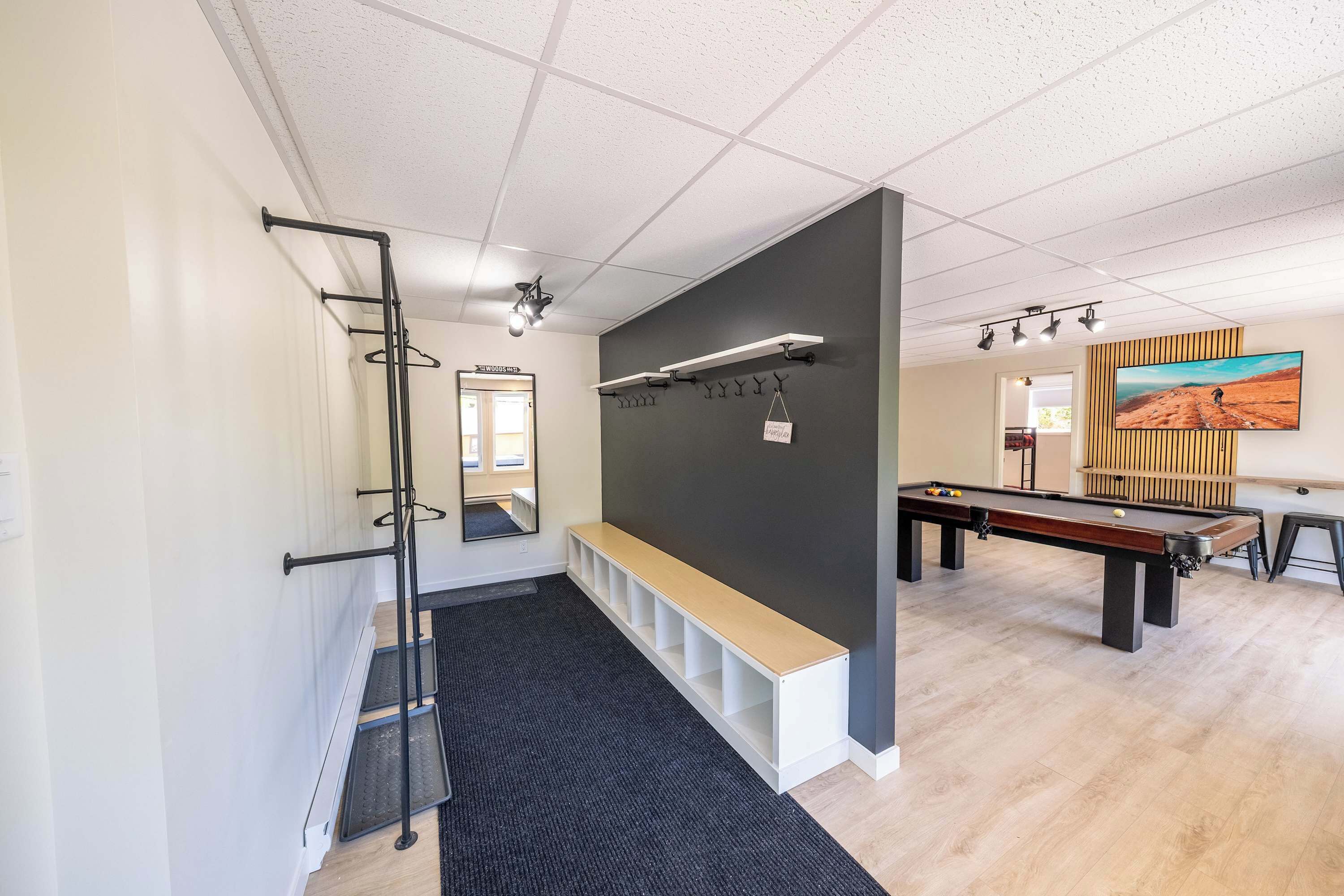 Et moderne poolområde indendørs med et billardbord, en bænk og et vægmonteret opbevaringsrum.