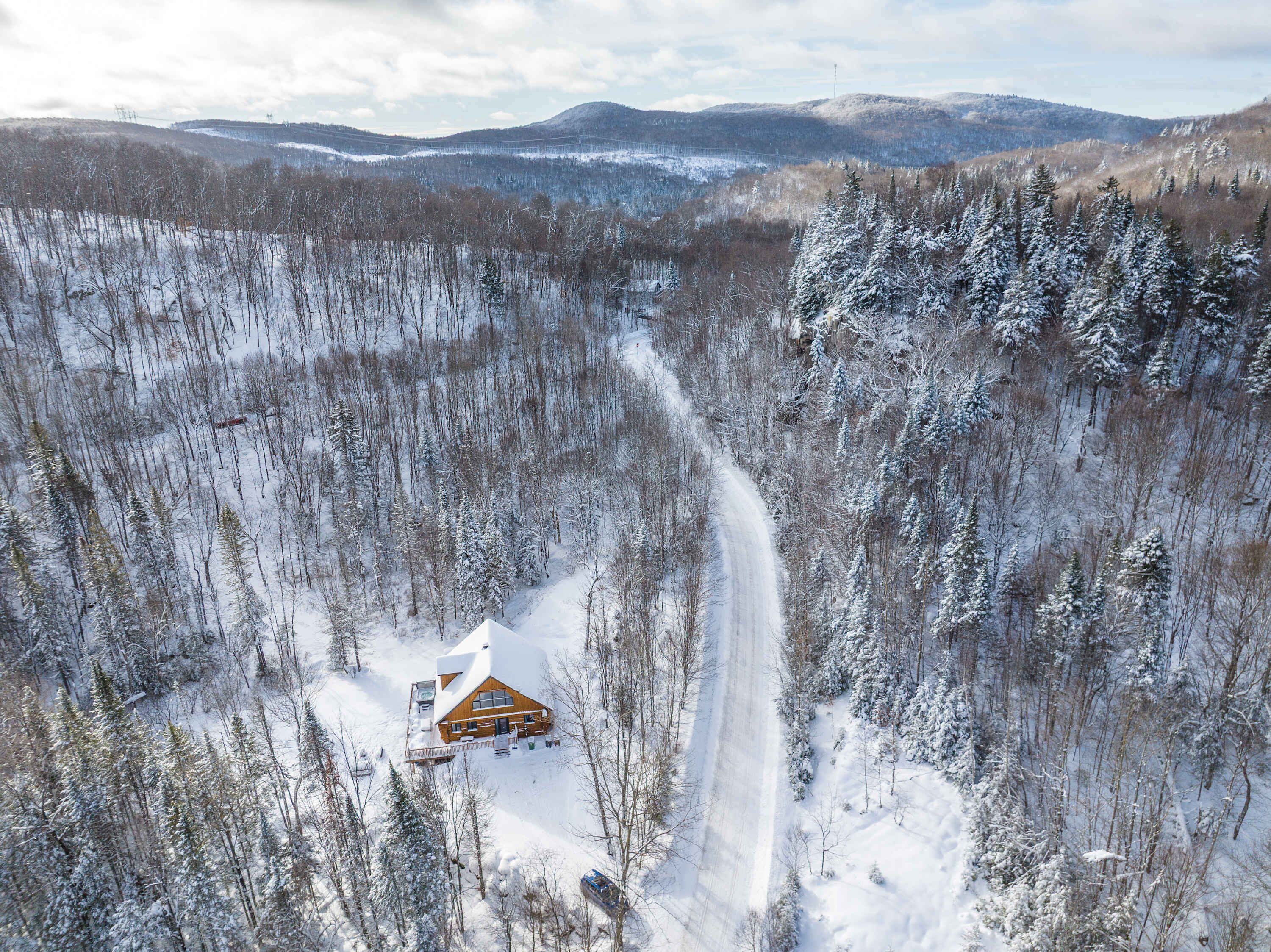 Une cabane entourée d’arbres couverts de neige, sous un ciel dégagé.