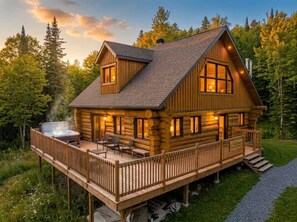 Une cabane en rondins avec une terrasse, un jacuzzi et une cheminée.