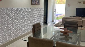 A modern living room with a glass-top dining table, beige sofas, and a patterned wall. - Center of Brasilia 5 minutes from the Esplanade of Ministries (Brasília)