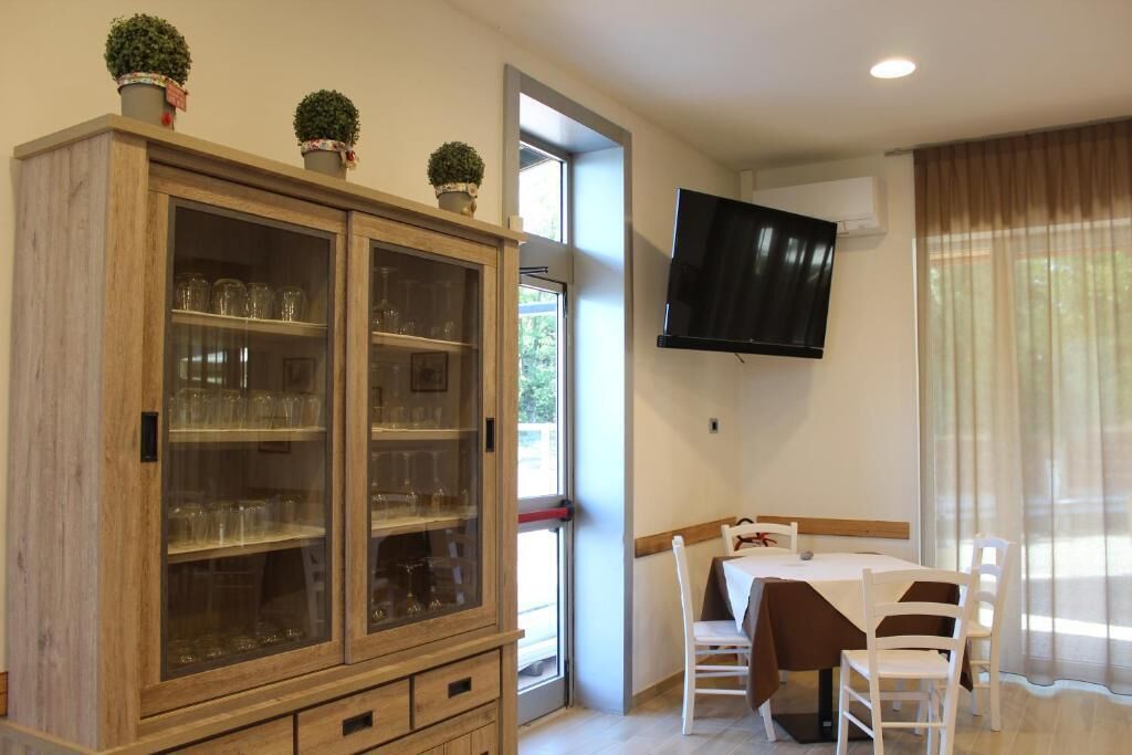 A dining area with a wooden cabinet, a table with chairs, and a TV mounted on the wall.