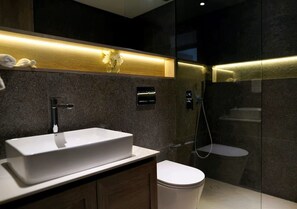 Een moderne badkamer met een witte wastafel, toilet en douche.