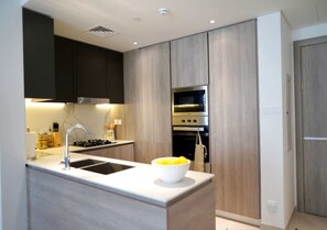 Apartamento luxo, 2 quartos | Cozinha privada | Geladeira, micro-ondas, cooktop, talheres/pratos/utensílios de cozinha