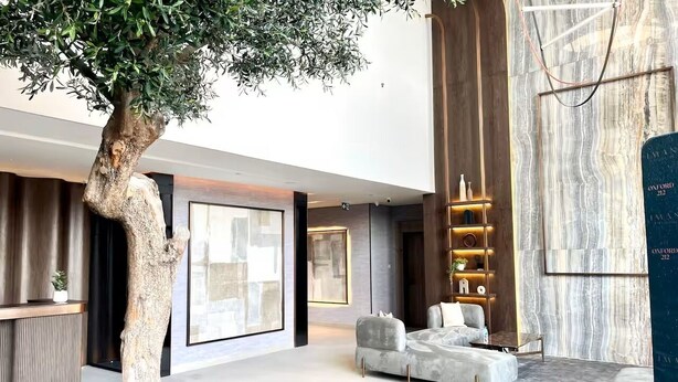 Een moderne woonkamer met een grote boom, een zithoek en een marmeren wand.