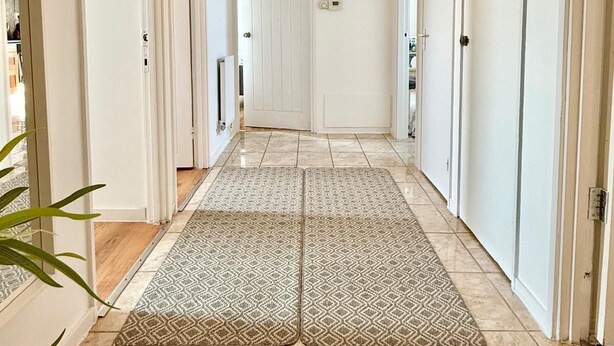 A hallway with a patterned rug, white doors, and a ceiling light.