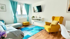 A modern living room with a sofa, yellow armchair, white chair, and a TV mounted on the wall.