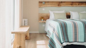 A bedroom with a wooden headboard, a bedside table with a vase of flowers, and a bed with a striped blanket. - Mar Puro (Mafra)