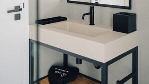 A modern bathroom with a white sink, black faucet, and a round mirror with a black frame. - Mar Puro (Mafra)