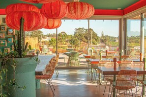 An outdoor dining area with tables and chairs, a cactus plant, and red lanterns. - Mar Puro (Mafra)