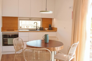 Una cocina moderna con armarios blancos, encimera de madera y una mesa redonda con sillas de mimbre.