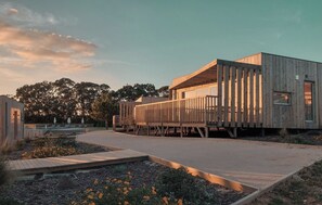 A modern wooden structure with a flat roof, surrounded by a landscaped garden with pathways and seating areas. - Mar Puro (Mafra)