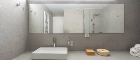 A modern bathroom with a large mirror, a rectangular sink, and a towel rack.