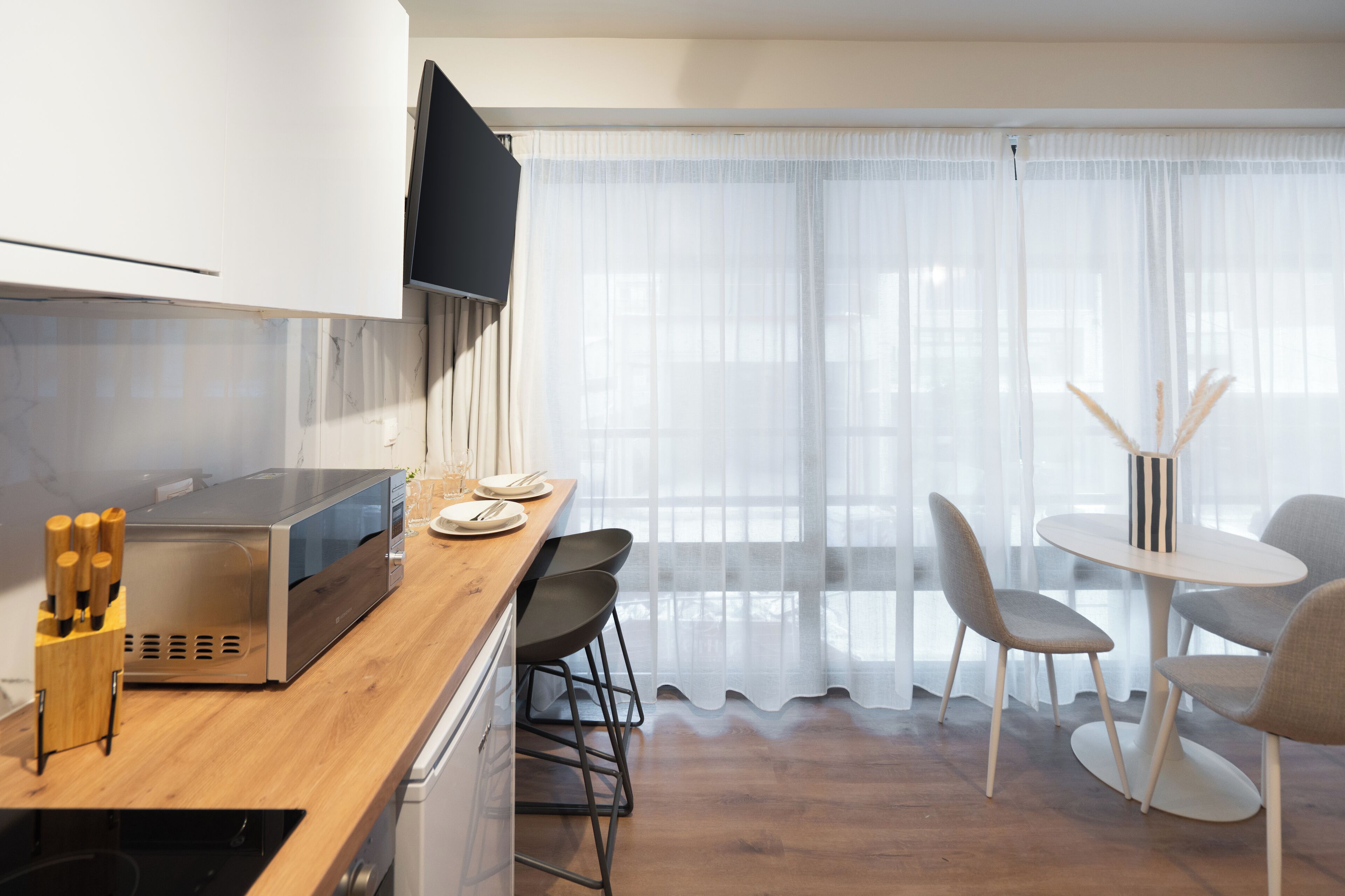 Una cocina moderna con microondas, encimera de madera y taburetes de bar.