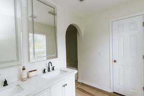 A bathroom with a white sink, a large mirror, and a white door. - Beachside Bliss: 4BR Home in Palm Coast Paradise (Palm Coast)