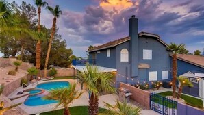 Ein Haus mit Pool, umgeben von Palmen und einem blauen Himmel mit Wolken.