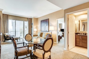 Une chambre d’hôtel comprenant un coin repas, un canapé, une table basse, une télévision et un coin cuisine.