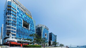 A modern hotel with a blue facade, multiple floors, and a distinctive curved structure.