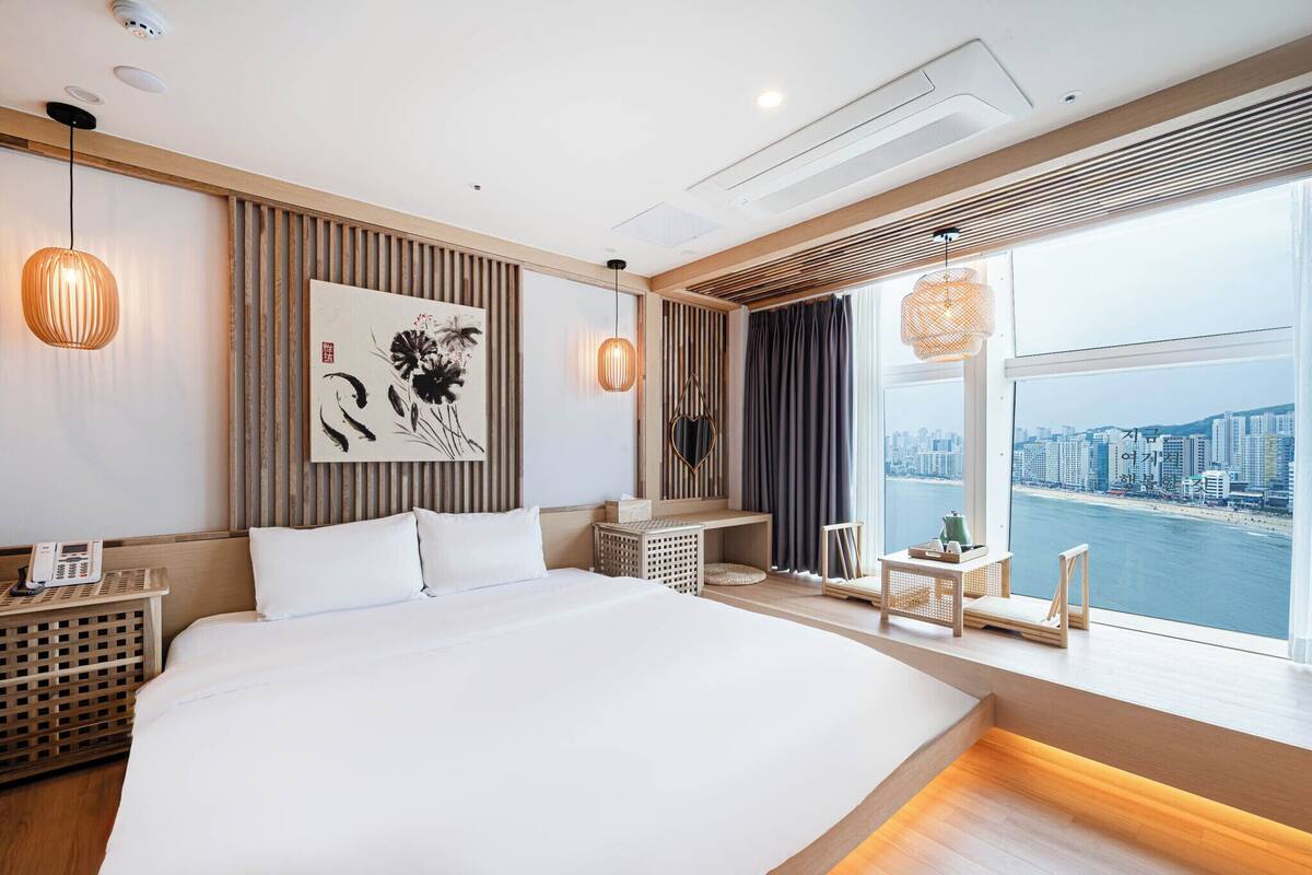 Una habitación de hotel moderna con una cama grande, vistas a la ciudad y una pared decorativa de madera.