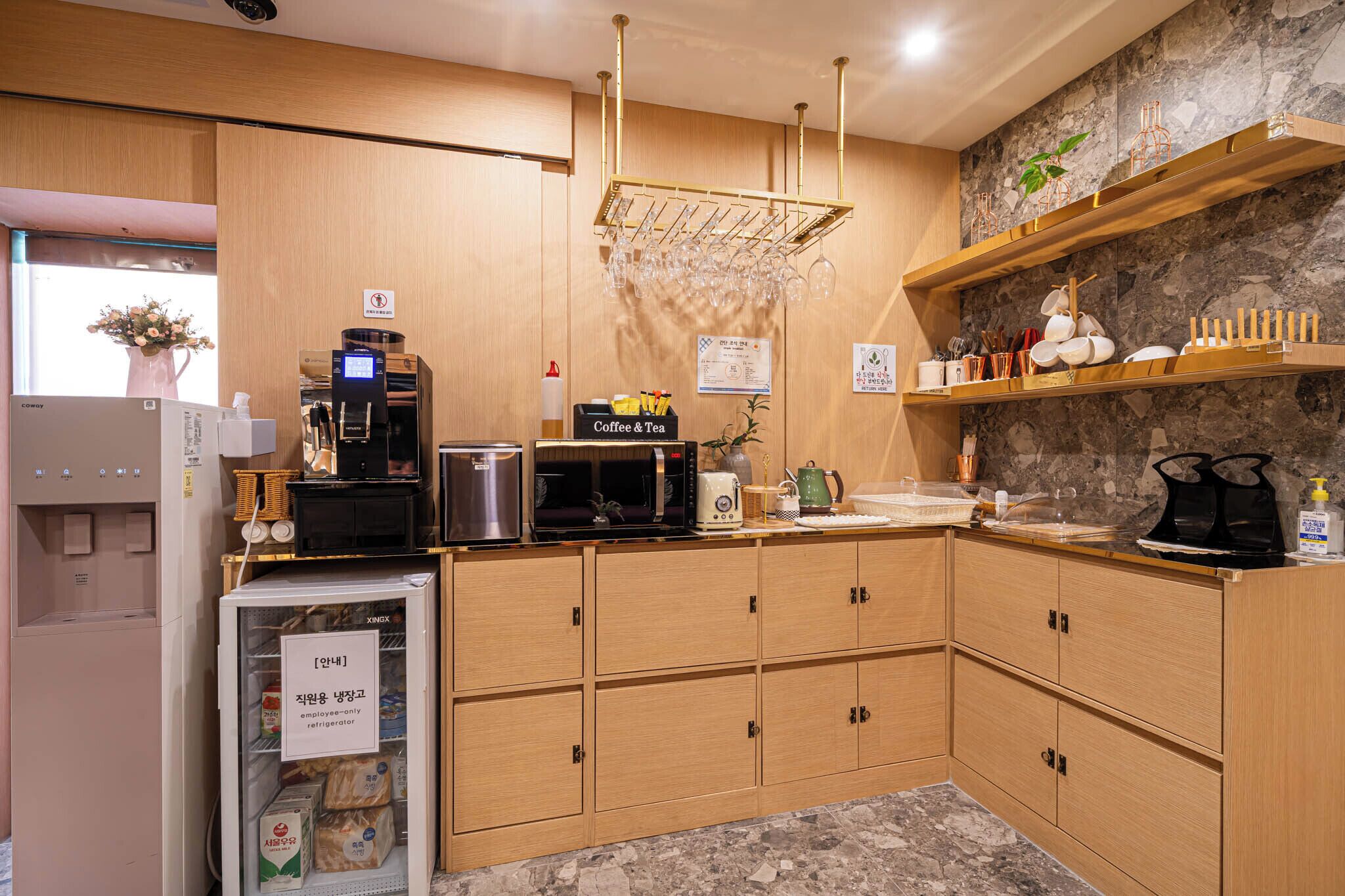 A kitchen with wooden cabinets, a coffee machine, a microwave, and a refrigerator.