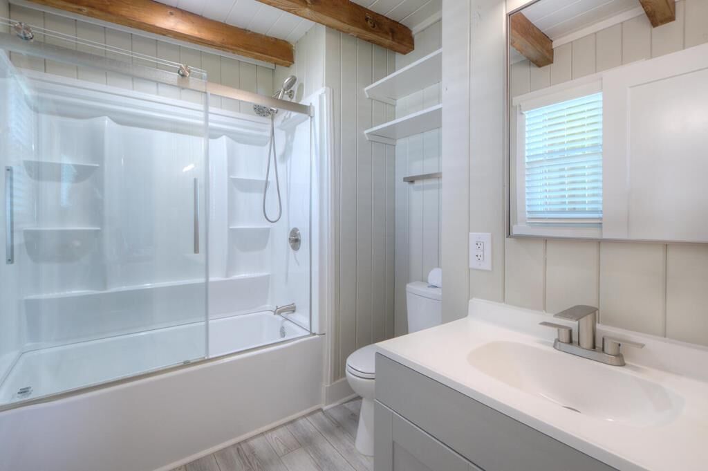 A modern bathroom with a glass-enclosed shower, a white sink, and a toilet.