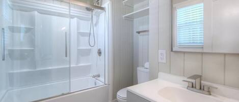 A modern bathroom with a glass-enclosed shower, a white sink, and a toilet.